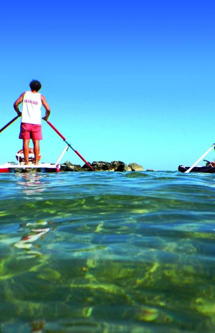 Two people on paddle boats at sea.